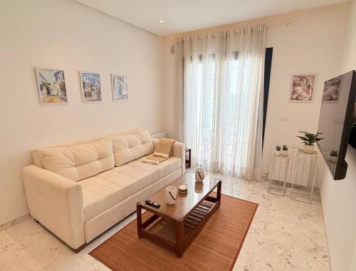a living room with a white couch and a table at Breeze La Marsa in Tunis