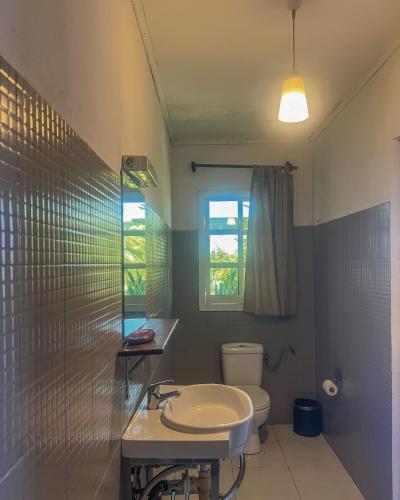 a bathroom with a sink and a toilet and a window at Hotel Jardin de la Paix in Moroni