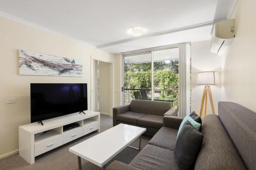 a living room with a couch and a flat screen tv at Solara at Aqua Mantra in Nelson Bay