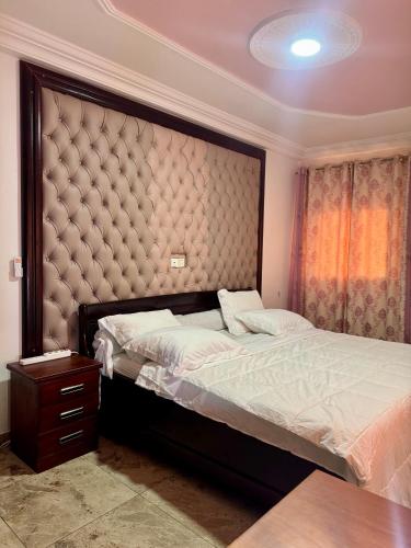 a bedroom with a bed and a large headboard at L Arche in Douala