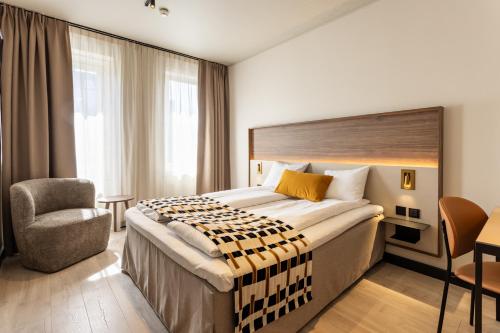 ein Hotelzimmer mit einem großen Bett und einem Stuhl in der Unterkunft Quality Hotel Augustin in Trondheim
