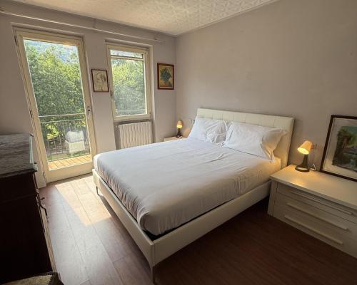 a bedroom with a white bed with two windows at Il Ranch in Baveno