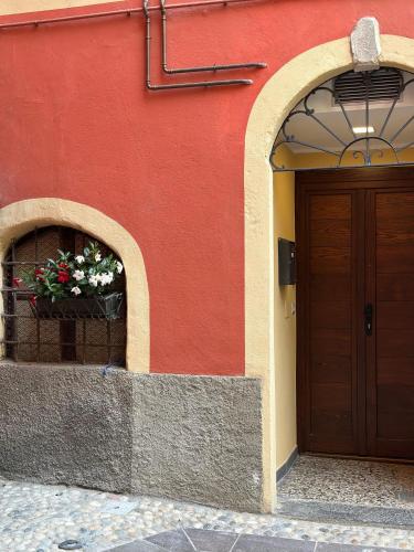 a red building with a door and a flower pot at Dimora di Aida Lugano Lake in Porlezza