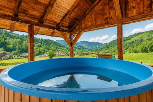 a hot tub in a wooden house with a view of mountains at Casa LA CIOTIC in Săcuieu
