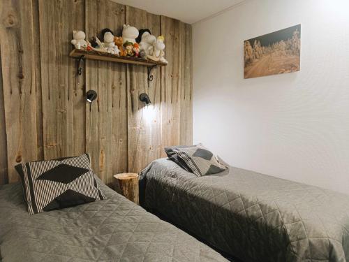 a bedroom with two beds and a wooden wall at Revontuli 6 in Syöte