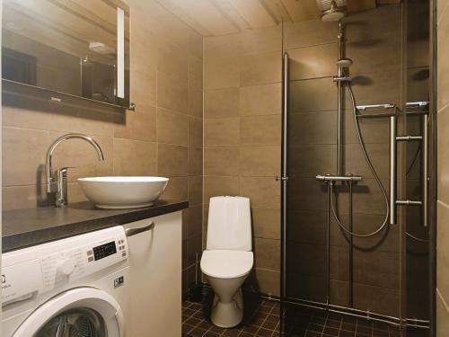 a bathroom with a toilet and a sink and a washing machine at Revontuli 6 in Syöte