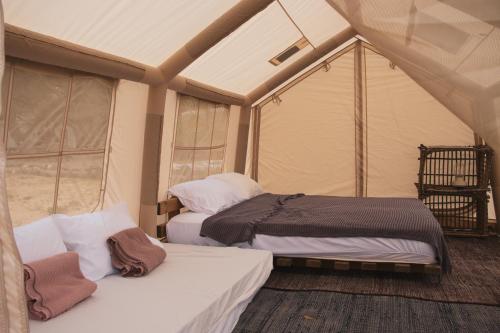 a bedroom with two beds in a tent at Mosh Achziv Beach in Gesher HaZiw
