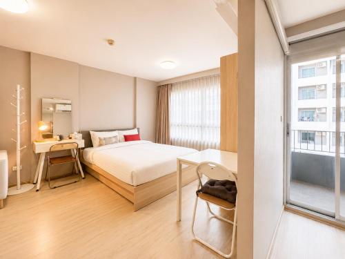a bedroom with a bed and a desk and a window at Spacious Studio Near BTS Kitchen & Washer in Amphoe Phra Khanong