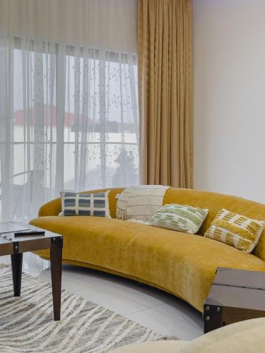 a yellow couch in a living room with a window at Luxury Balcony Apartment at THE HIDDEN DOMUS I Prestige Apartment in Accra