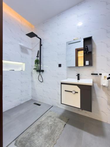a white bathroom with a sink and a mirror at Luxury Balcony Apartment at THE HIDDEN DOMUS I Prestige Apartment in Accra
