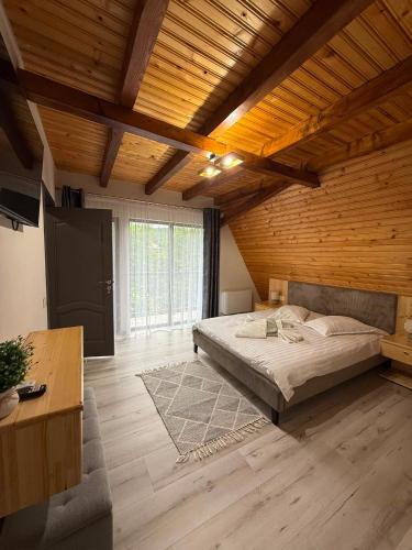 a large bedroom with a bed and a wooden ceiling at Complex Turistic Hor'A in Slănic