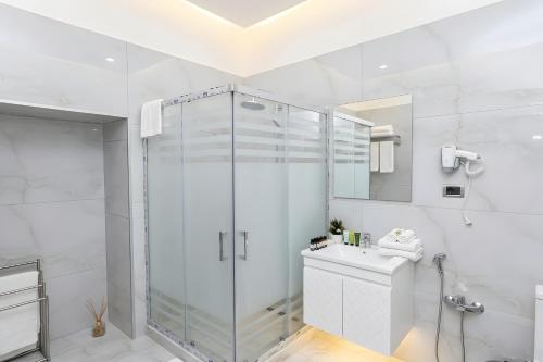 a white bathroom with a shower and a sink at Epicenter Hotel Baku in Baku