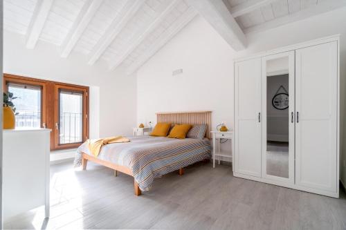 a white bedroom with a bed with orange pillows at L'appartamento giallo zafferano in Fanano