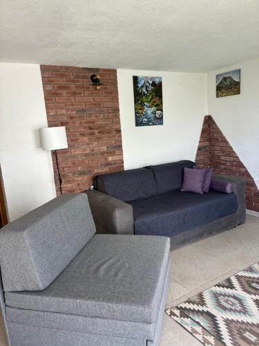 a living room with a blue couch and a brick wall at Hillside Apartment Kruna in Babušnica