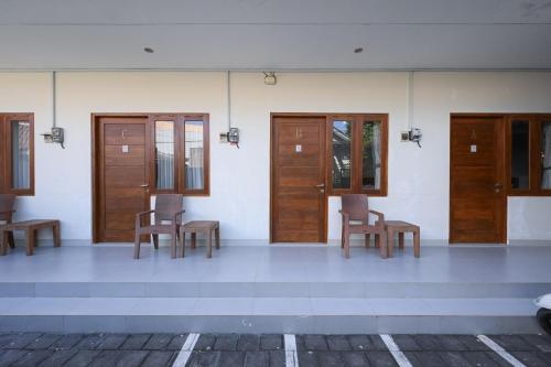 a room with wooden doors and tables and chairs at RedDoorz Plus at Kencana Residence Jimbaran in Jimbaran