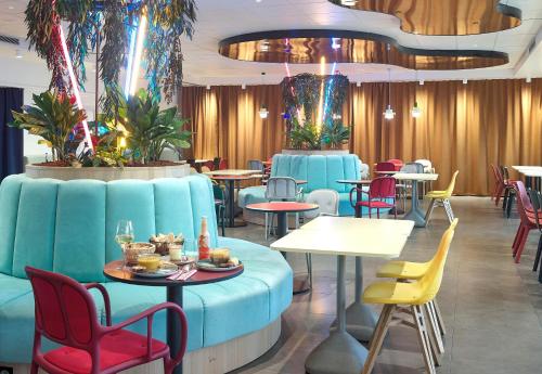 a restaurant with a blue couch and tables and chairs at B&B HOTEL Paris 17 Batignolles in Paris