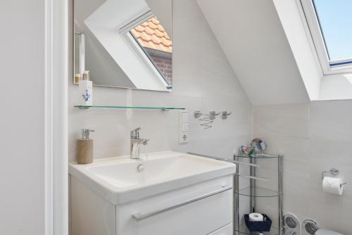 a white bathroom with a sink and a window at Grachtenrefugium in Greetsiel