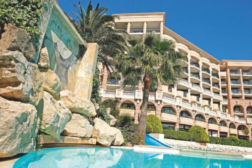 a hotel with a swimming pool in front of a building at Résidence La Palme d’Azur – Cannes in Cannes