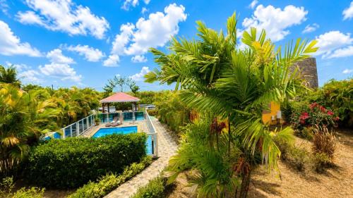a resort pool with a gazebo and palm trees at Les Palmes du Moulin in Saint-Louis