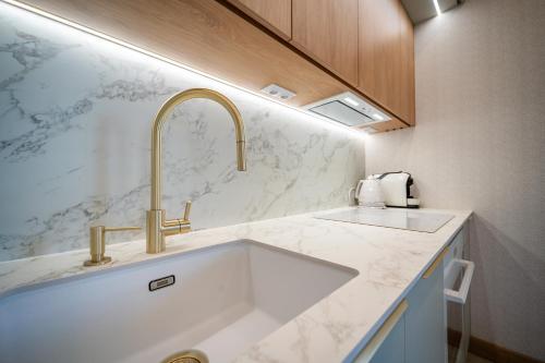a kitchen with a sink and gold faucet at Apartament K&M 13 in Mikołajki