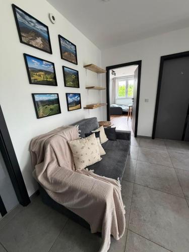 a living room with a couch and pictures on the wall at The Country Stop Apartment in Łęki