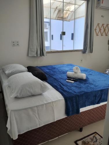 a bedroom with a bed with a blue blanket and a window at House Hotel Slz in São Luís