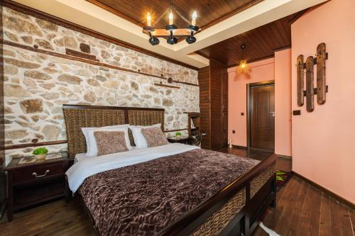 a bedroom with a large bed with a stone wall at Villa Ploski in Ploski
