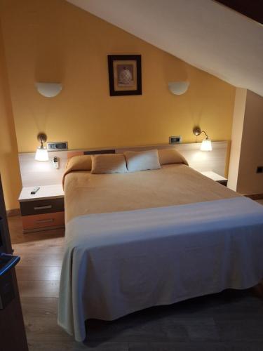 a bedroom with a large bed with two lights on it at Hostal Doña Juana in Ávila