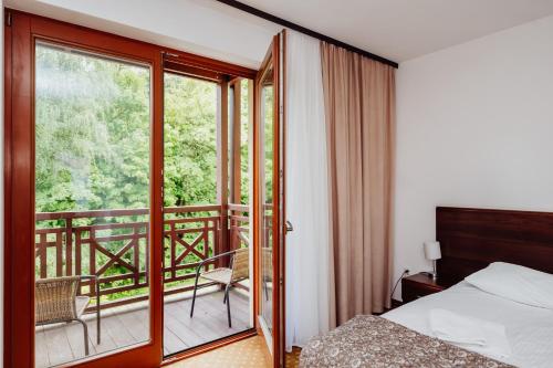 ein Hotelzimmer mit Bett und Balkon in der Unterkunft Instytut Zdrowia Sofra FIT & SPA in Karpacz