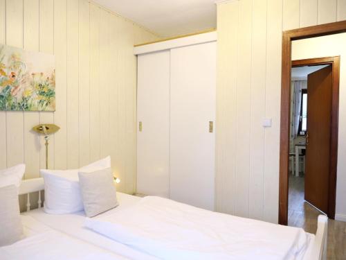 a bedroom with a white bed and a mirror at Fischerweg-39-Whg-2-Amrum in Westerland