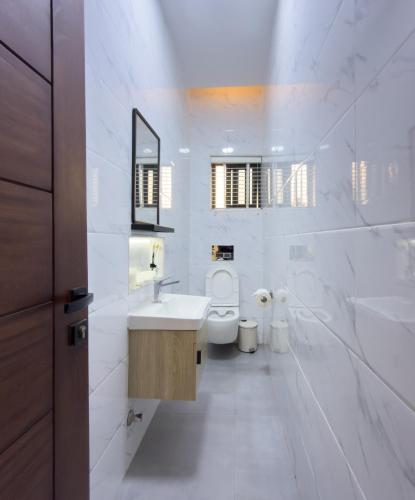 a white bathroom with a sink and a toilet at Horizon Apartment at THE HIDDEN DOMUS I Pool View in Accra