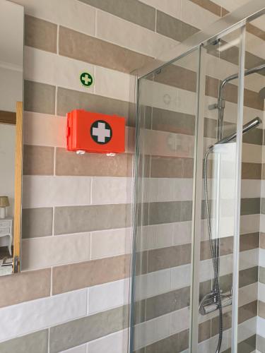 a bathroom with a shower with a red box on the wall at A Quinta in Vila Nova de Milfontes