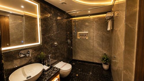 a bathroom with a sink and a toilet and a shower at Hotel Sainik Grand in Varanasi