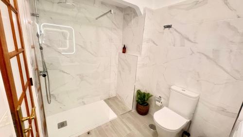 a white bathroom with a shower and a toilet at Club Atlantis with views in Adeje