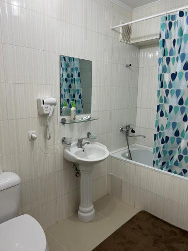 a bathroom with a sink and a toilet and a tub at АпартаментРадугаВест1 in Koshkolʼ