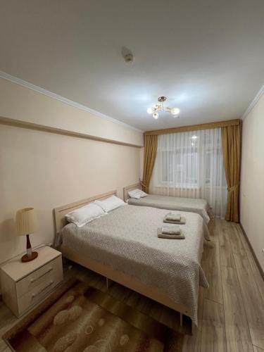 a bedroom with a large bed and a window at АпартаментРадугаВест1 in Koshkolʼ