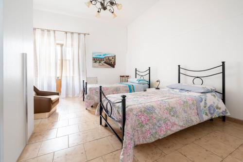 ein Schlafzimmer mit zwei Betten und einem Stuhl in der Unterkunft Db Apartment in Giurdignano