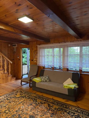 a living room with a couch and some windows at Domki Pod Lasem in Macharce