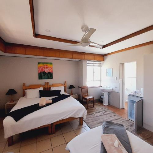 a bedroom with a large bed with a ceiling fan at Acorn Lodge & SKYDECK in Potchefstroom