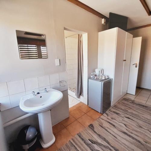 a bathroom with a white sink and a refrigerator at Acorn Lodge & SKYDECK in Potchefstroom
