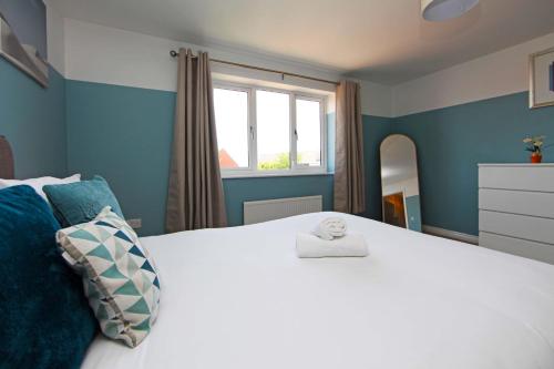 a bedroom with a white bed with blue walls and a window at Autumn Heights Apartments in Telford