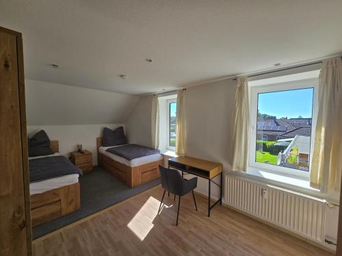 a bedroom with two beds and a desk and a window at Ferienwohnung Küstennah in Großenwiehe