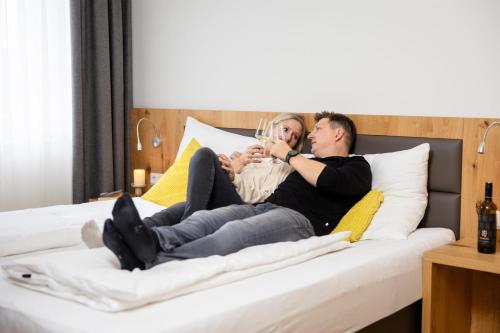 a man and woman sitting on a bed drinking wine at Ferienwohnung Königshofer in Neusiedl am See