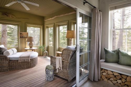 a screened porch with a bed and chairs and windows at Hidden Pond Resort in Kennebunkport