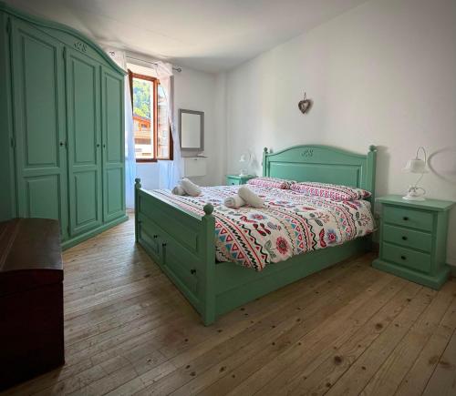 a bedroom with a green bed and green cabinets at Appartamento Novecento in Enguiso