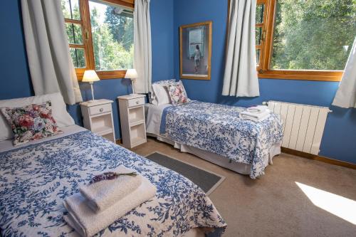 1 dormitorio con 2 camas y paredes azules en El lugar de la Flor en San Carlos de Bariloche
