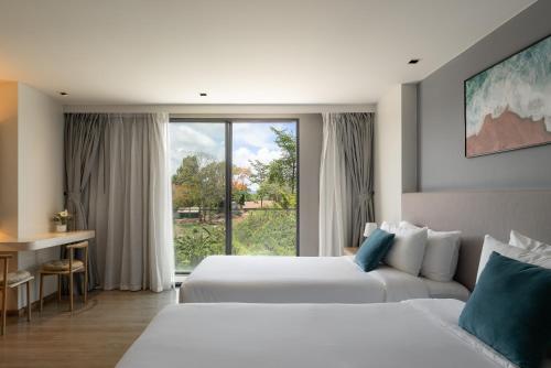 a hotel room with two beds and a window at La Vita Bao in Phuket