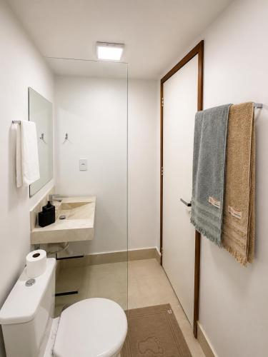 a white bathroom with a toilet and a sink at Loft Novo, Duplex, bem ventilado in Aparecida de Goiânia