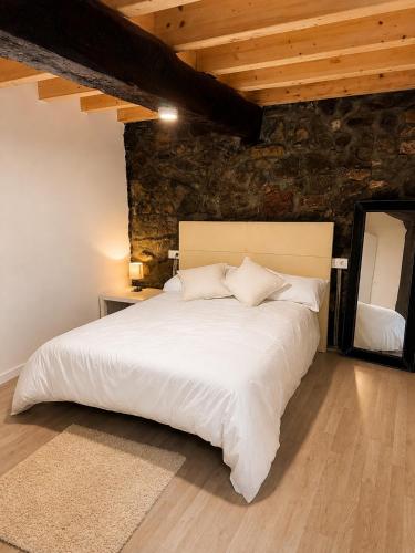 a bedroom with a large white bed with a stone wall at Posada Inés in Castro-Urdiales