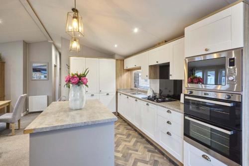 a kitchen with white cabinets and a vase of flowers on a counter at The Haven Lodge with Hot Tub in York